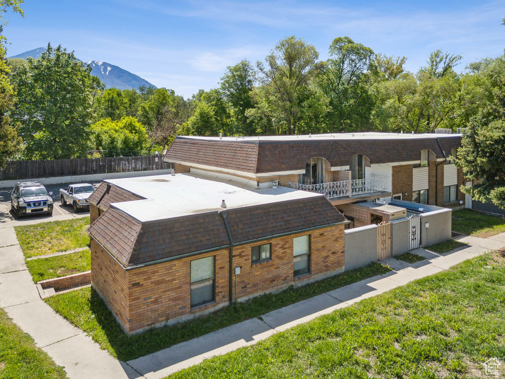 View of front of property with brick siding, roof with shingles, and a mountain view