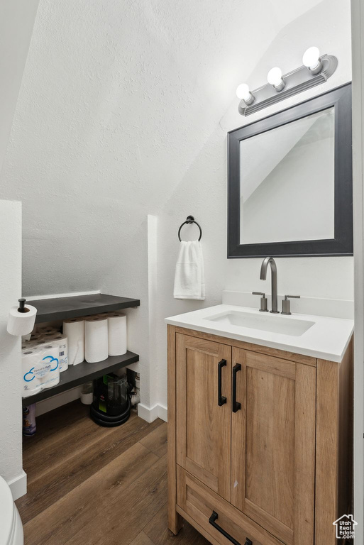 Bathroom with vaulted ceiling, wood finished floors, and vanity