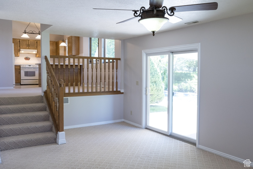 Stairs with a ceiling fan, carpet, and baseboards