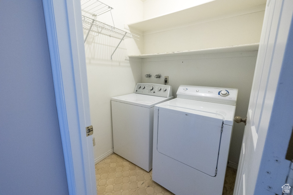 Laundry room with washing machine and clothes dryer and light floors