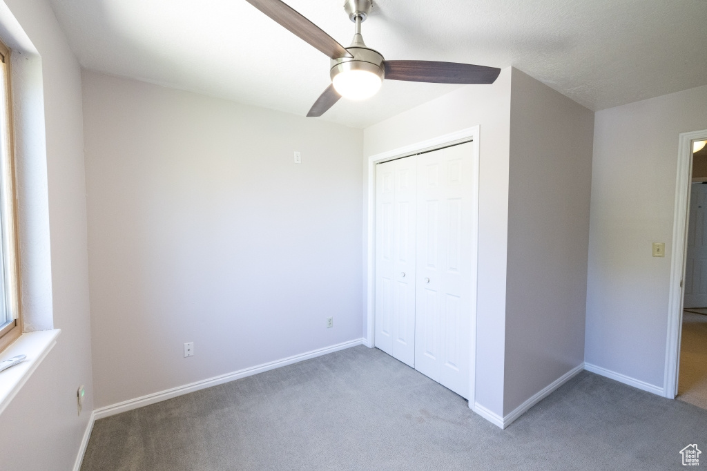 Unfurnished bedroom with light carpet, baseboards, a closet, and ceiling fan