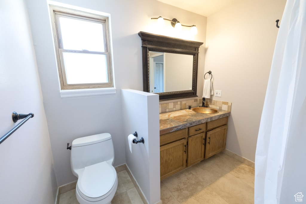 Full bath with vanity, toilet, decorative backsplash, and baseboards