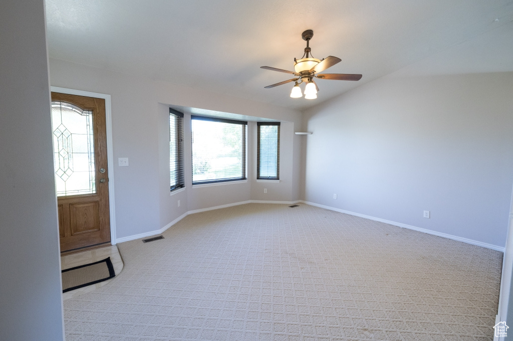 Entrance foyer featuring light carpet, a ceiling fan, baseboards, and vaulted ceiling