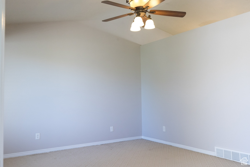 Unfurnished room with light carpet, a ceiling fan, baseboards, and lofted ceiling