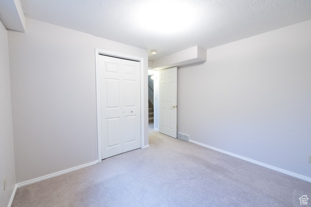 Unfurnished bedroom with light colored carpet, a closet, and baseboards