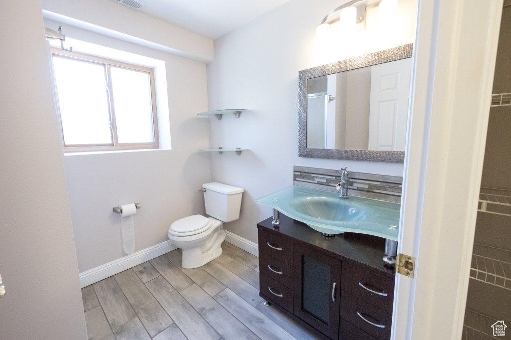 Bathroom featuring vanity, wood finished floors, toilet, and baseboards