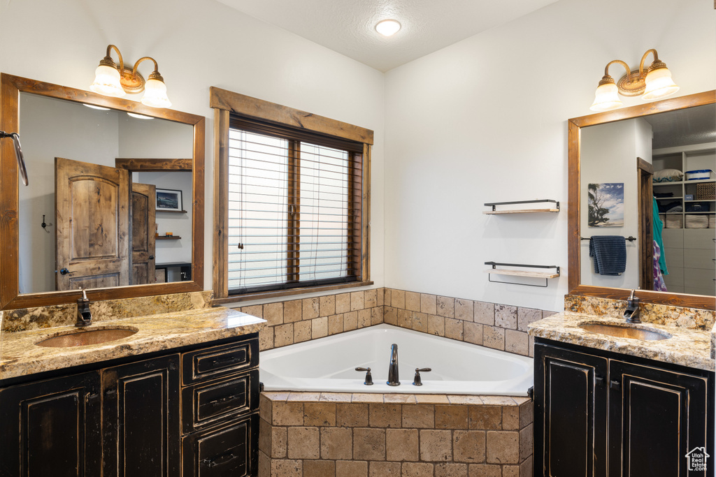 Bathroom featuring two vanities and a garden tub