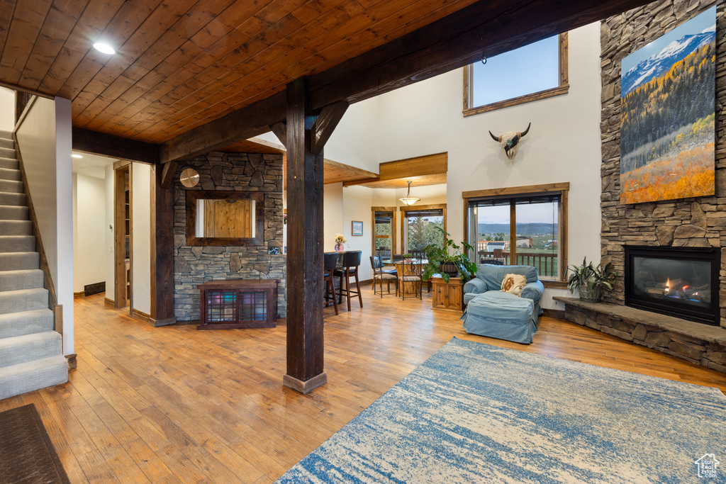 Living room featuring a fireplace, stairway, wood ceiling, wood-type flooring, and baseboards