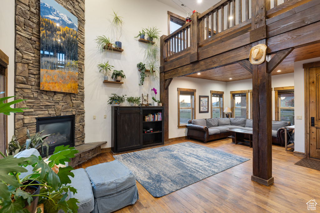 Living area with a high ceiling, hardwood / wood-style floors, a stone fireplace, and recessed lighting