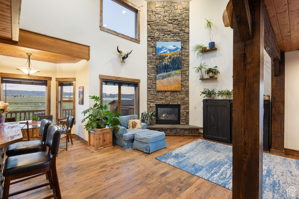 Living room with a fireplace, wood finished floors, a high ceiling, and wooden ceiling