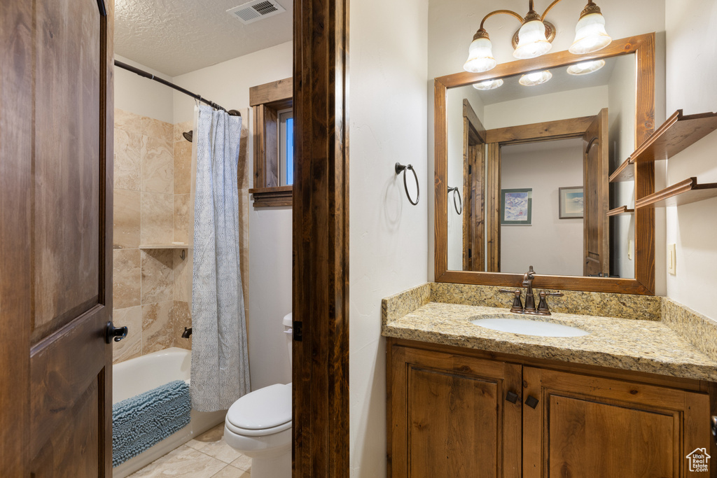 Bathroom with vanity, toilet, shower / tub combo with curtain, and a textured ceiling