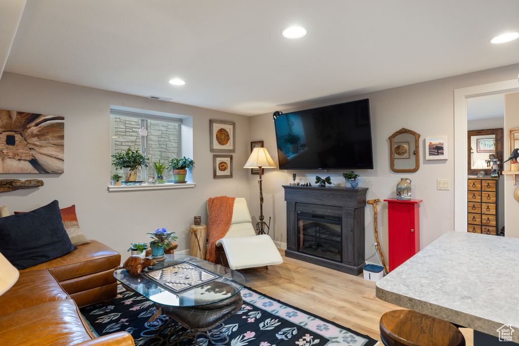 Living room featuring recessed lighting, wood finished floors, and a glass covered fireplace