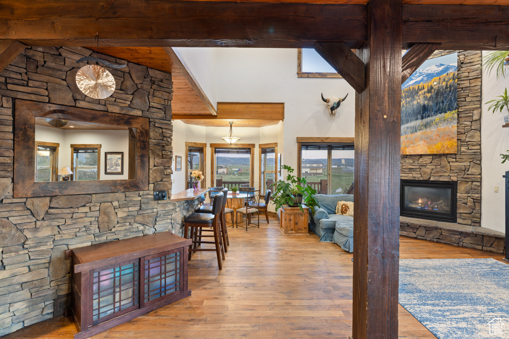 Dining area featuring beamed ceiling, hardwood / wood-style flooring, a fireplace, and a high ceiling