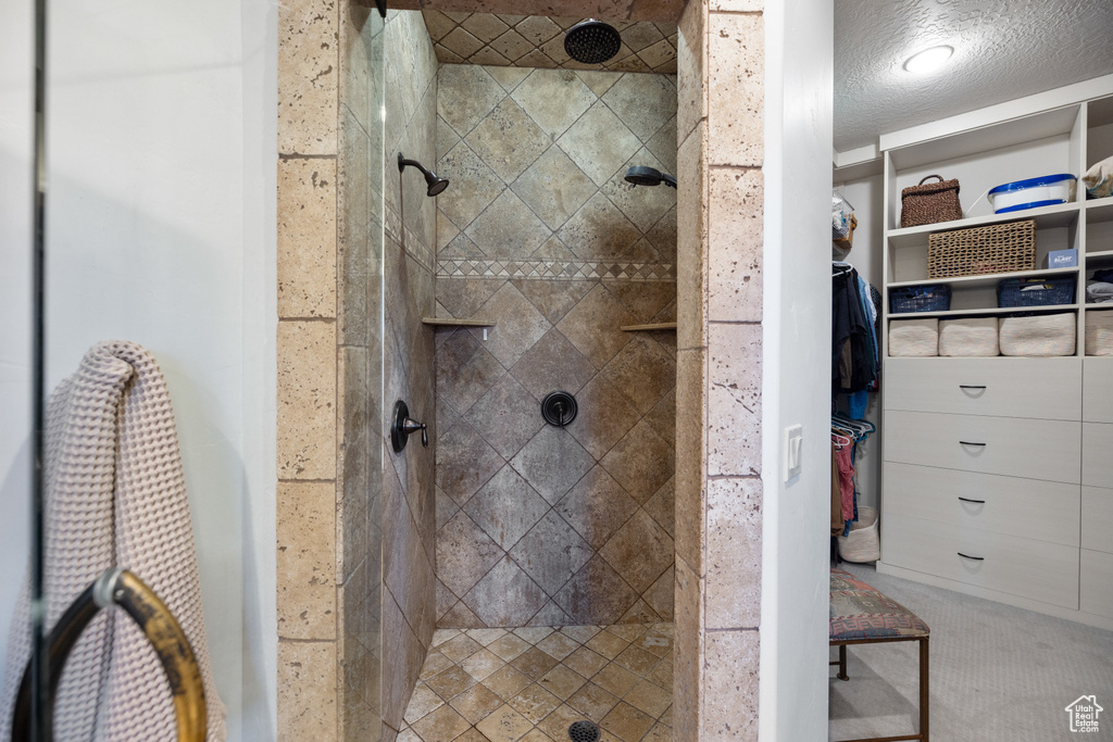 Full bath with a tile shower and a walk in closet