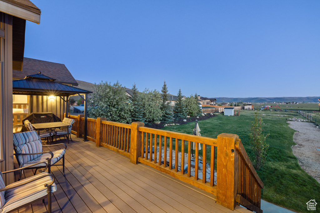 Wooden deck with a gazebo, outdoor dining area, and a yard