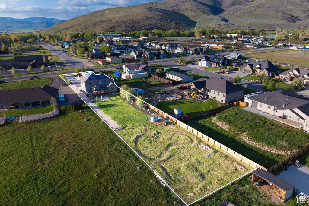 Aerial view of property and surrounding area with a mountain backdrop, nearby suburban area, and property boundaries highlighted