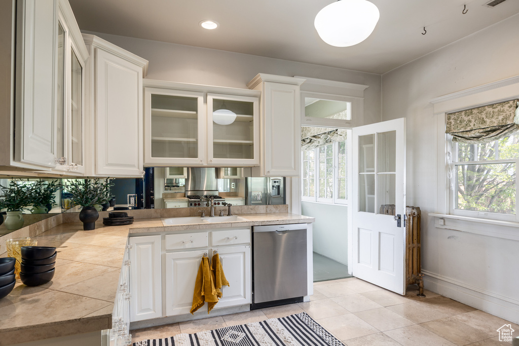 Kitchen featuring stainless steel dishwasher, white cabinetry, and glass insert cabinets