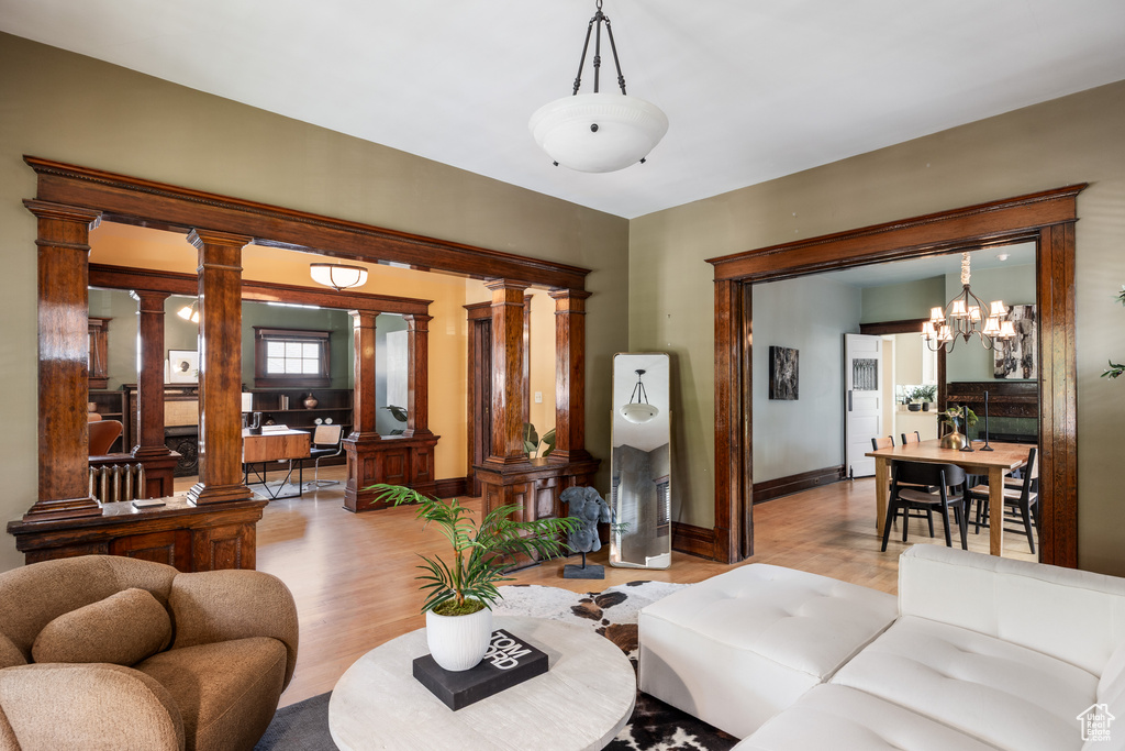Living area featuring wood finished floors, decorative columns, baseboards, and a chandelier