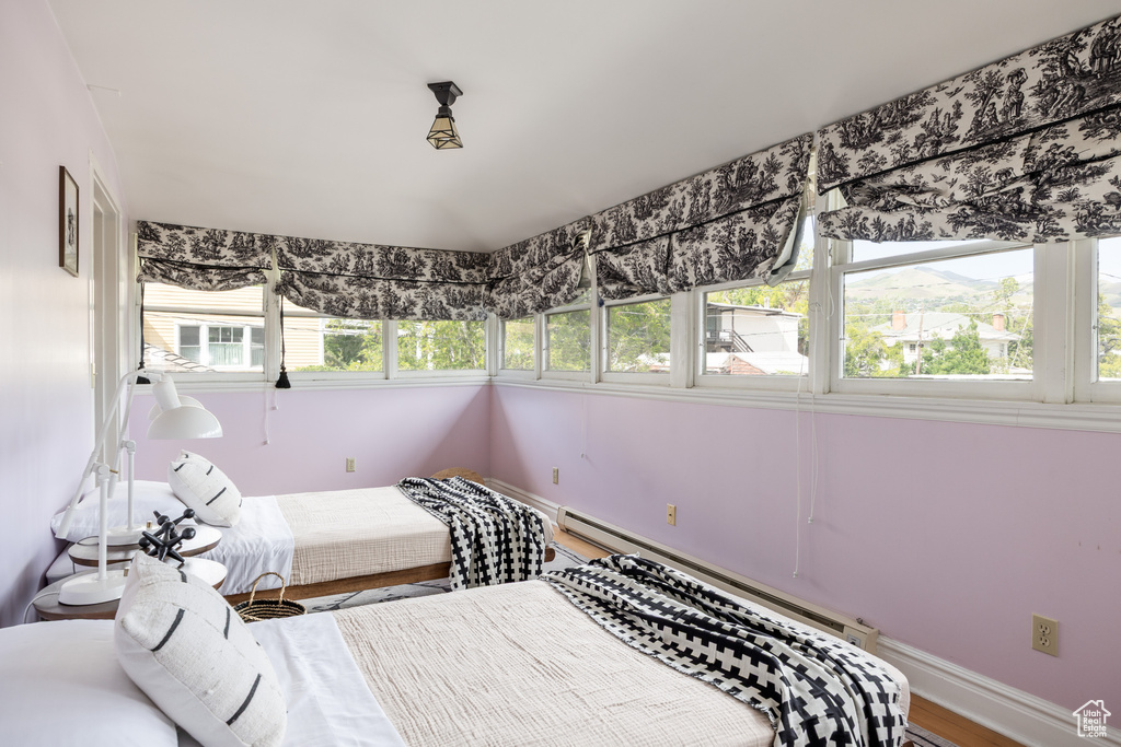 Bedroom featuring baseboard heating, baseboards, and wood finished floors