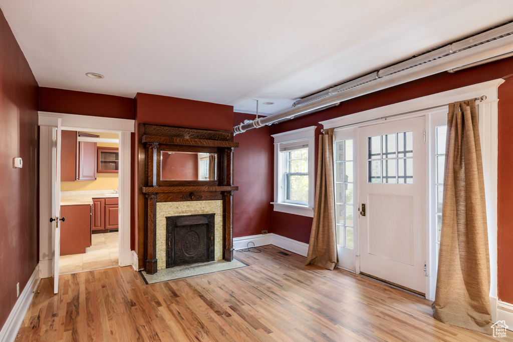 Entryway with light wood-style flooring, a fireplace with flush hearth, and baseboards