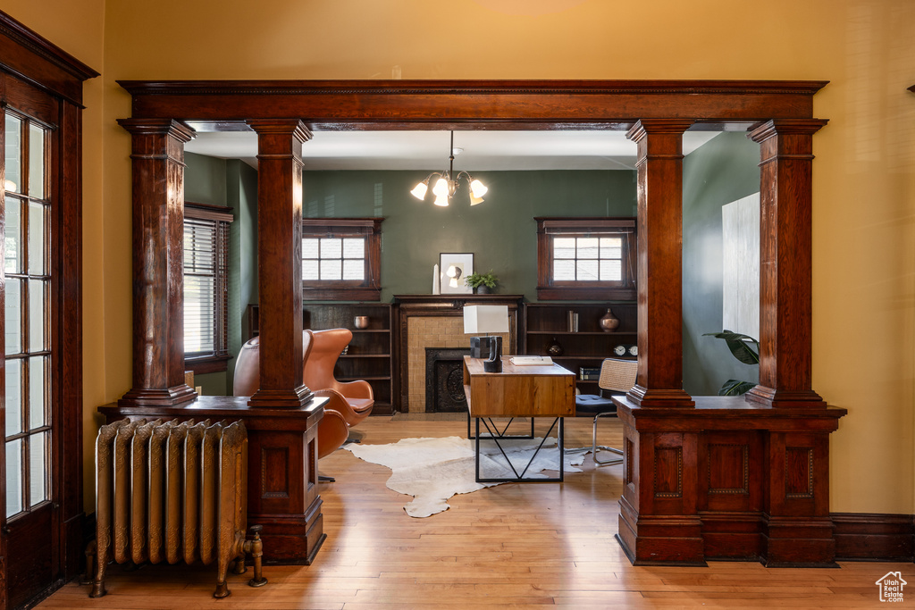 Office space featuring radiator heating unit, light wood finished floors, and a chandelier