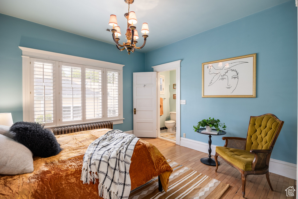 Bedroom featuring wood-type flooring, a chandelier, radiator heating unit, baseboards, and ensuite bathroom