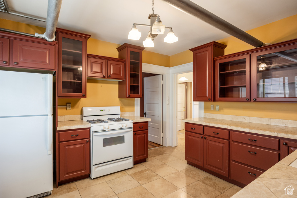 Kitchen featuring white appliances, glass insert cabinets, pendant lighting, light tile patterned floors, and a chandelier