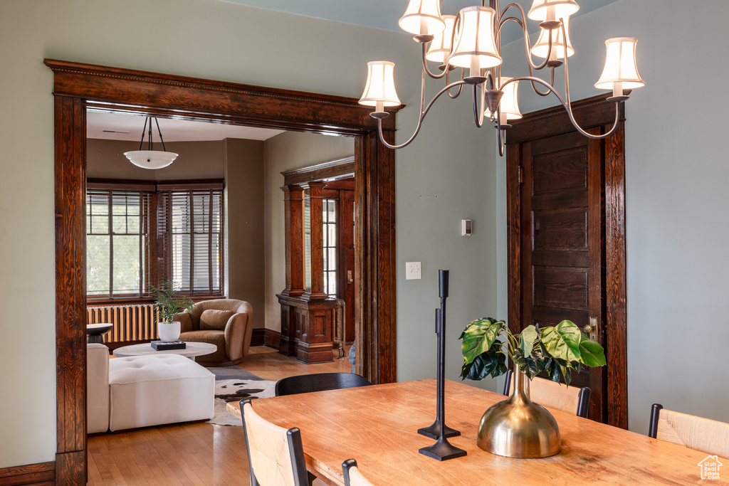 Dining space with radiator heating unit, wood finished floors, and a chandelier
