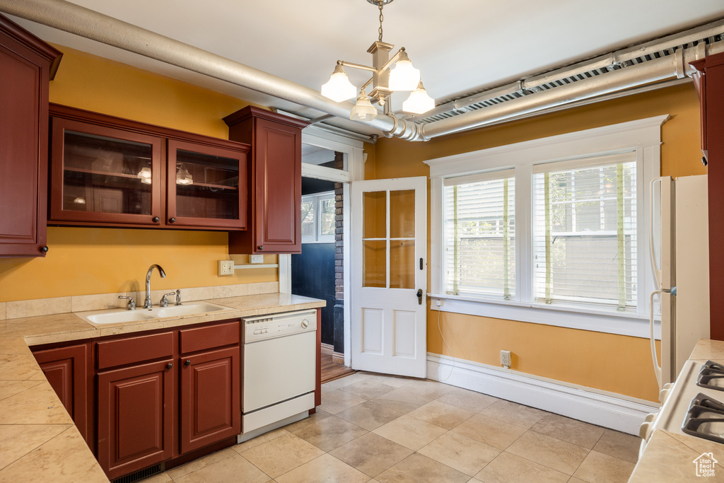 Kitchen with white appliances, a sink, light countertops, a chandelier, and decorative light fixtures