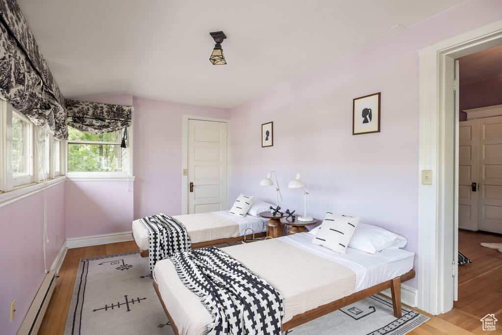 Bedroom with baseboard heating, light wood-style flooring, and baseboards