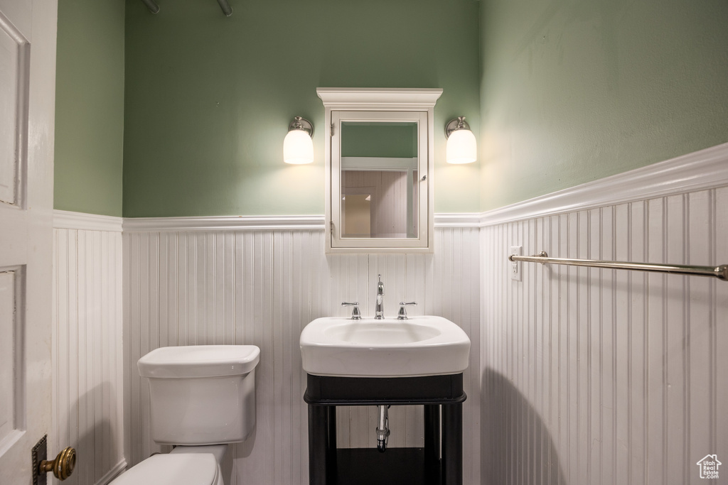 Half bathroom featuring a wainscoted wall and toilet