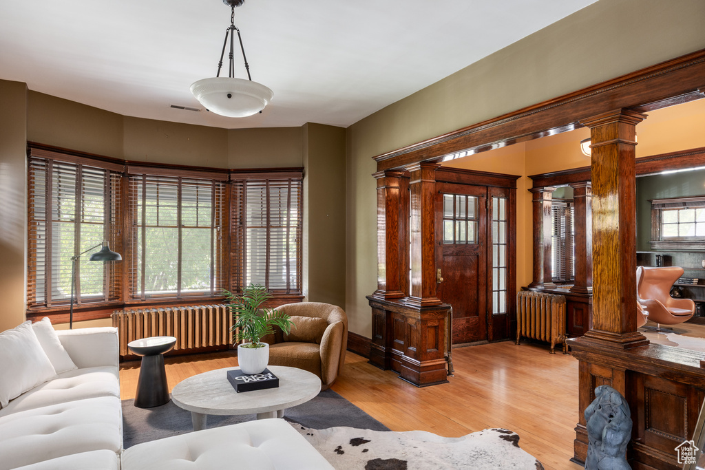 Living room featuring radiator, decorative columns, and light wood-style flooring