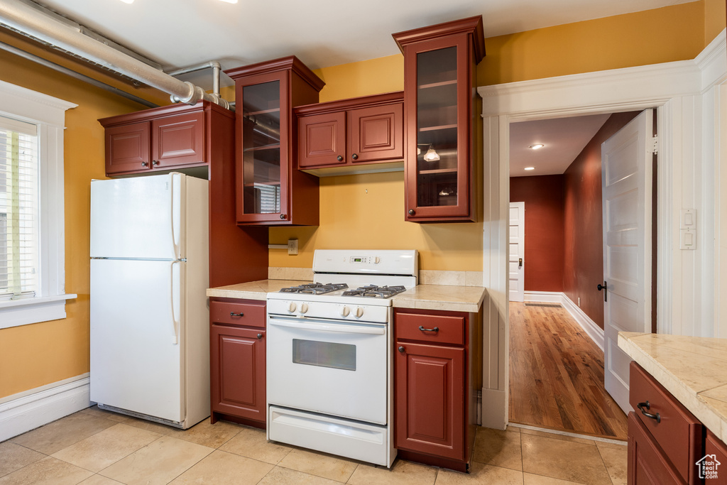 Kitchen featuring white appliances, light countertops, glass insert cabinets, light tile patterned floors, and recessed lighting