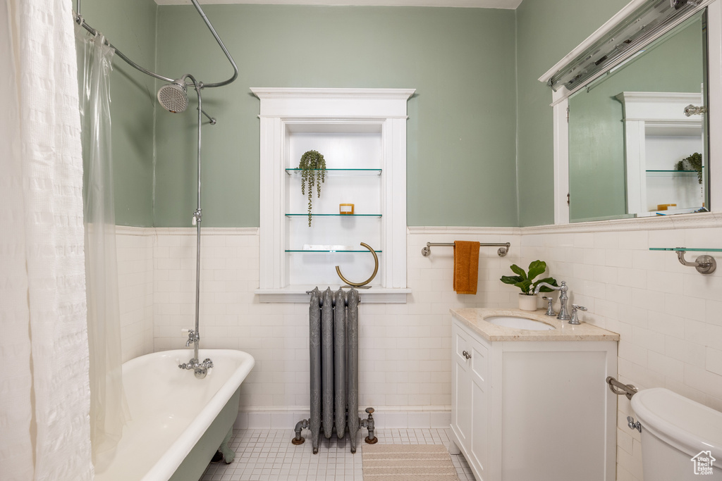 Full bath with radiator heating unit, tile walls, vanity, a wainscoted wall, and tile patterned flooring