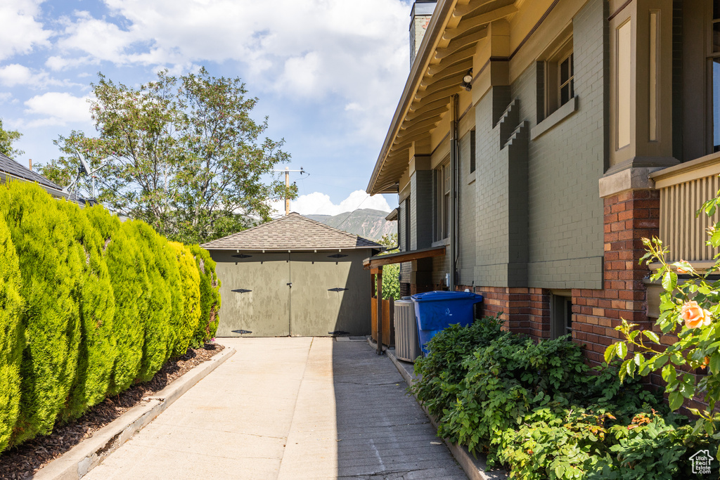 View of side of home featuring brick siding, an outdoor structure, and a chimney