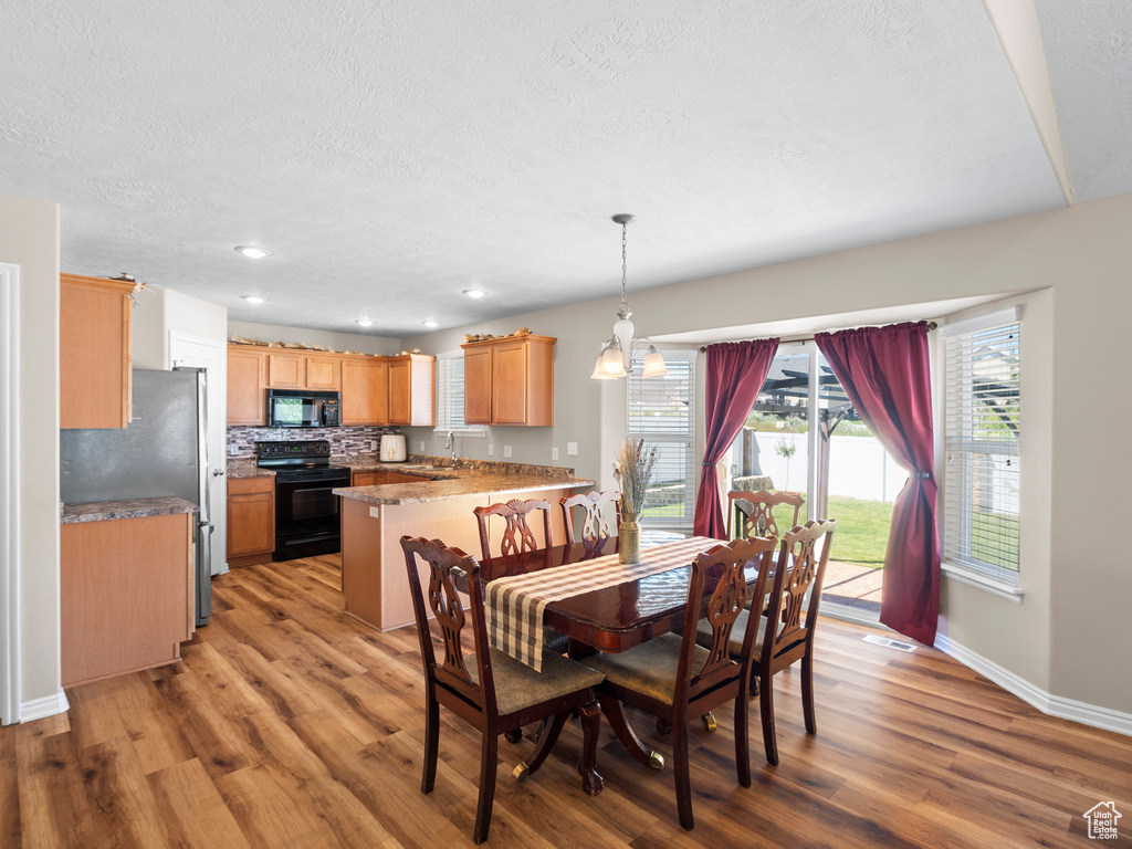 Dining area featuring light wood finished floors, baseboards, a textured ceiling, and recessed lighting