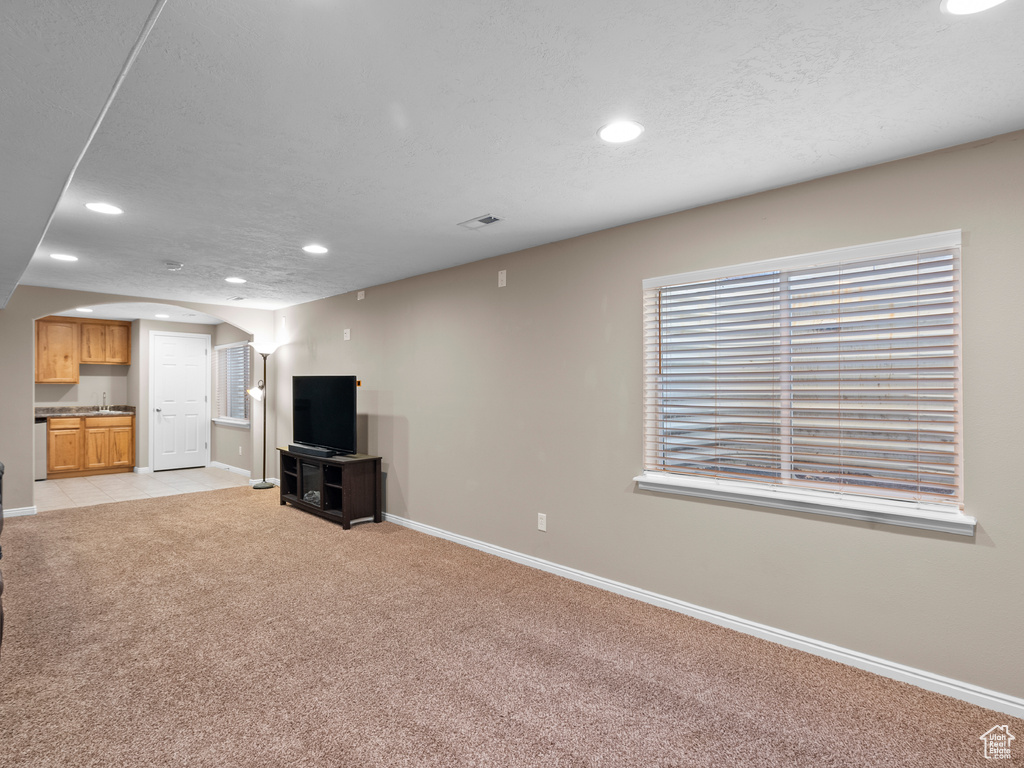 Unfurnished living room featuring recessed lighting, light colored carpet, baseboards, and arched walkways