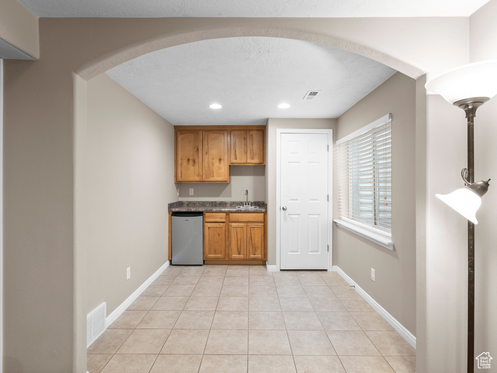 Kitchen featuring dishwashing machine, recessed lighting, arched walkways, a sink, and light tile patterned floors