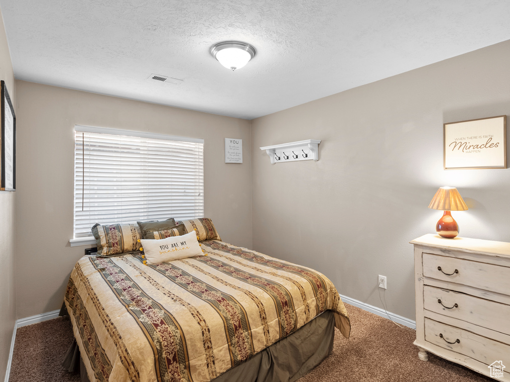 Bedroom with carpet, baseboards, and a textured ceiling
