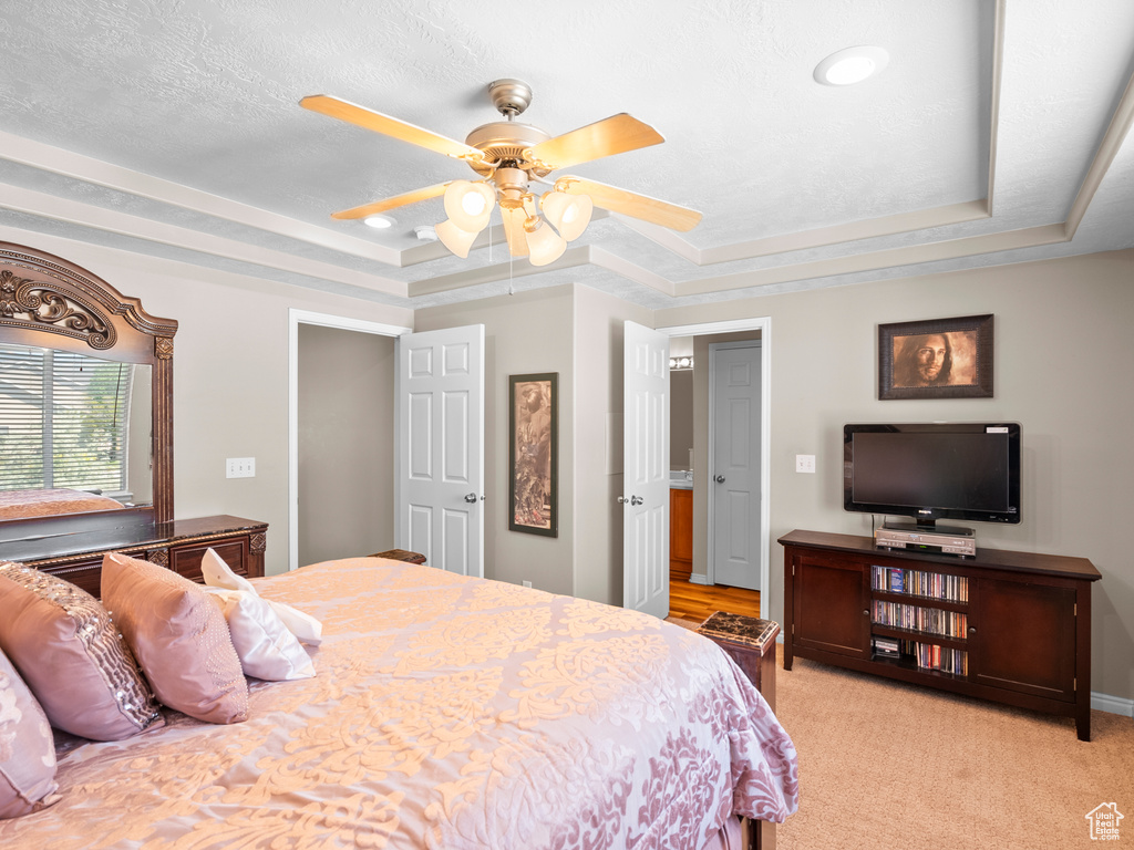 Bedroom featuring a tray ceiling, ceiling fan, and light carpet