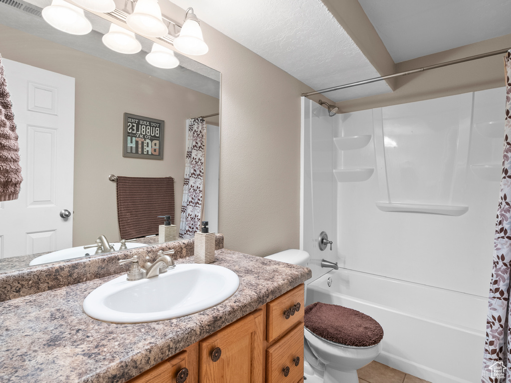 Bathroom with toilet, vanity, shower / tub combo with curtain, and tile patterned floors