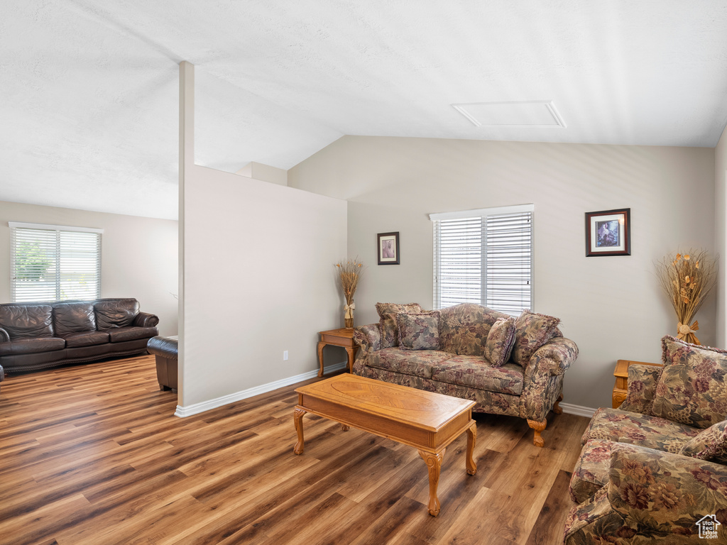 Living room with light wood-type flooring, vaulted ceiling, and baseboards