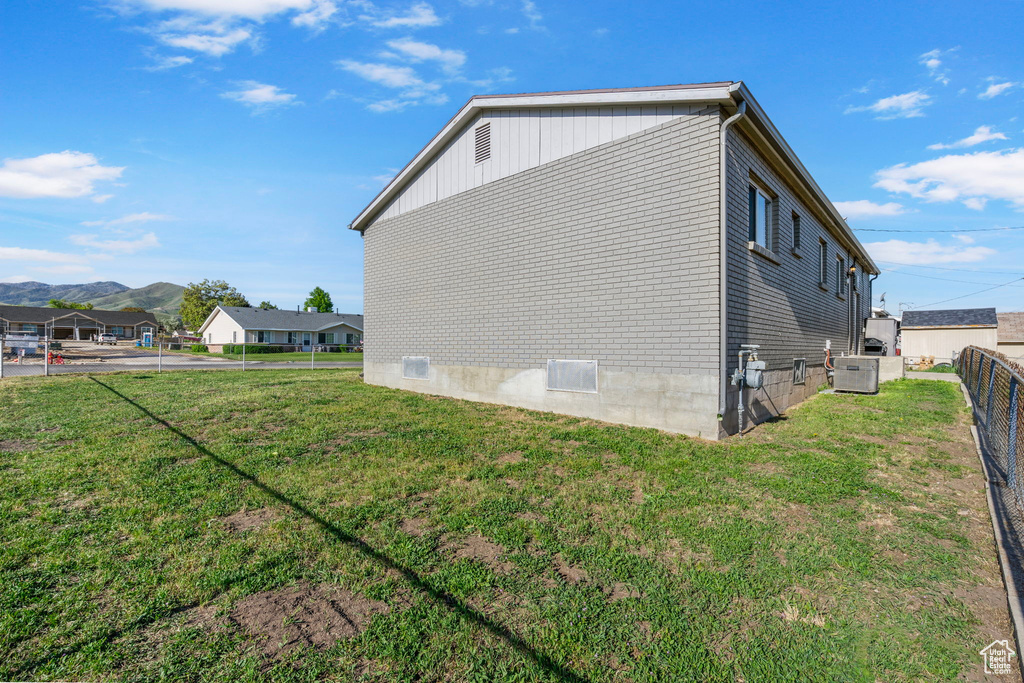 View of property exterior featuring central air condition unit, a mountain view, and brick siding