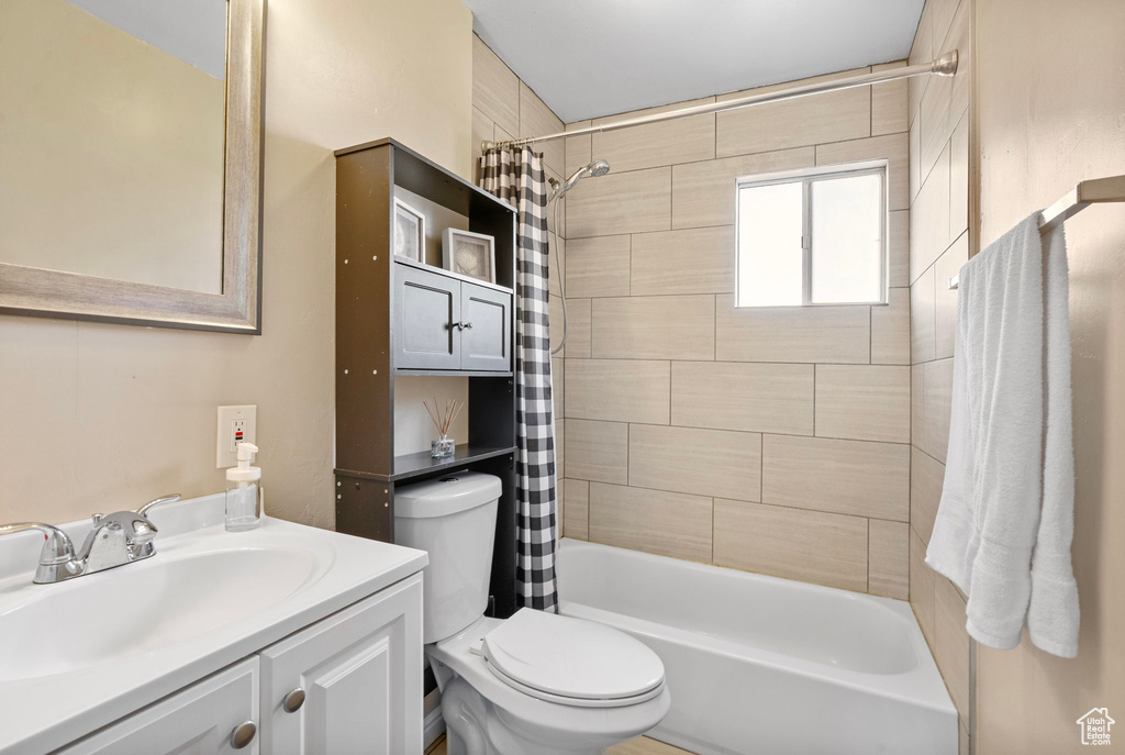Full bathroom with toilet, shower / bath combo, and vanity