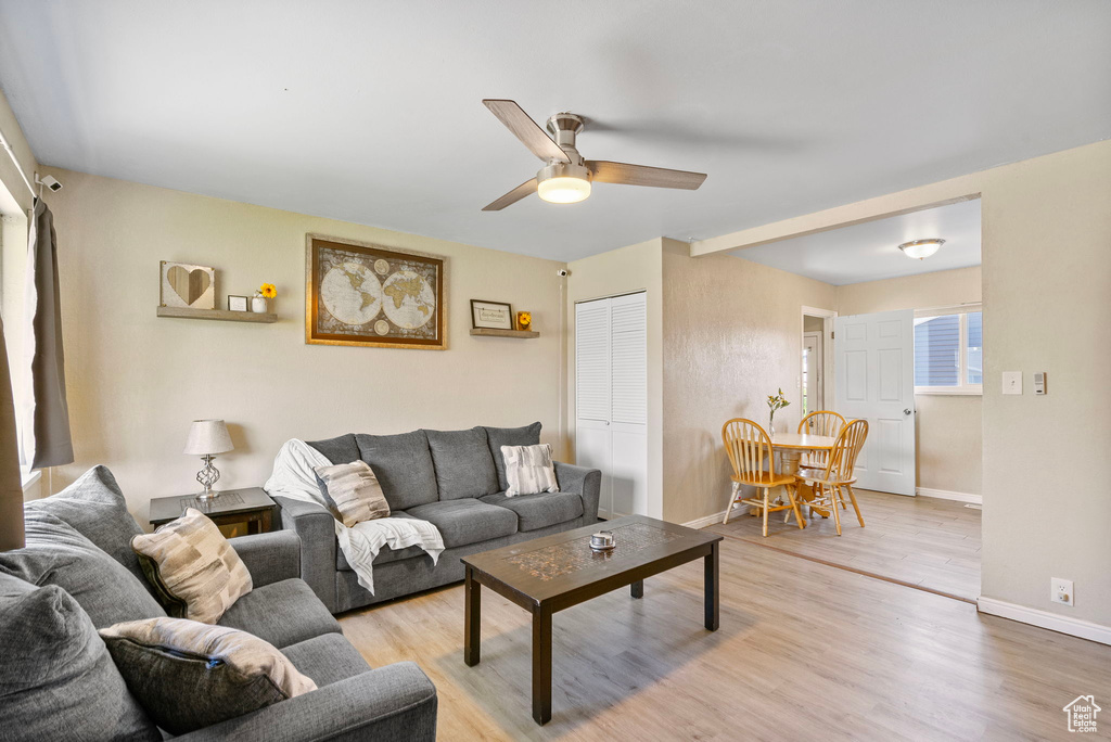 Living area featuring ceiling fan, baseboards, and light wood finished floors