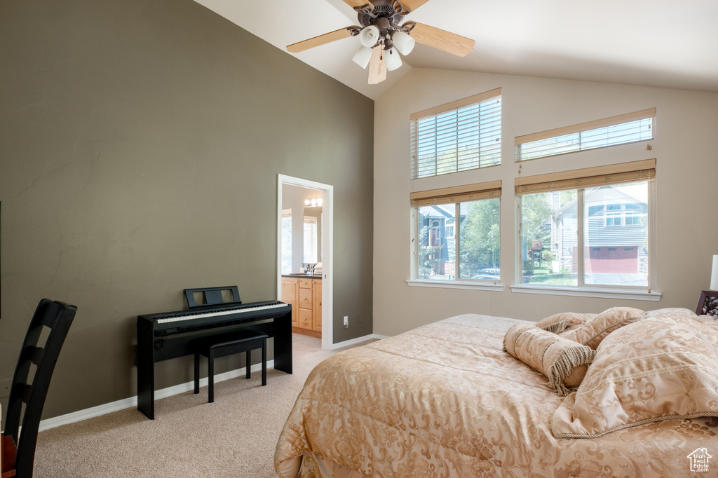 Bedroom with high vaulted ceiling, light colored carpet, multiple windows, baseboards, and ensuite bath