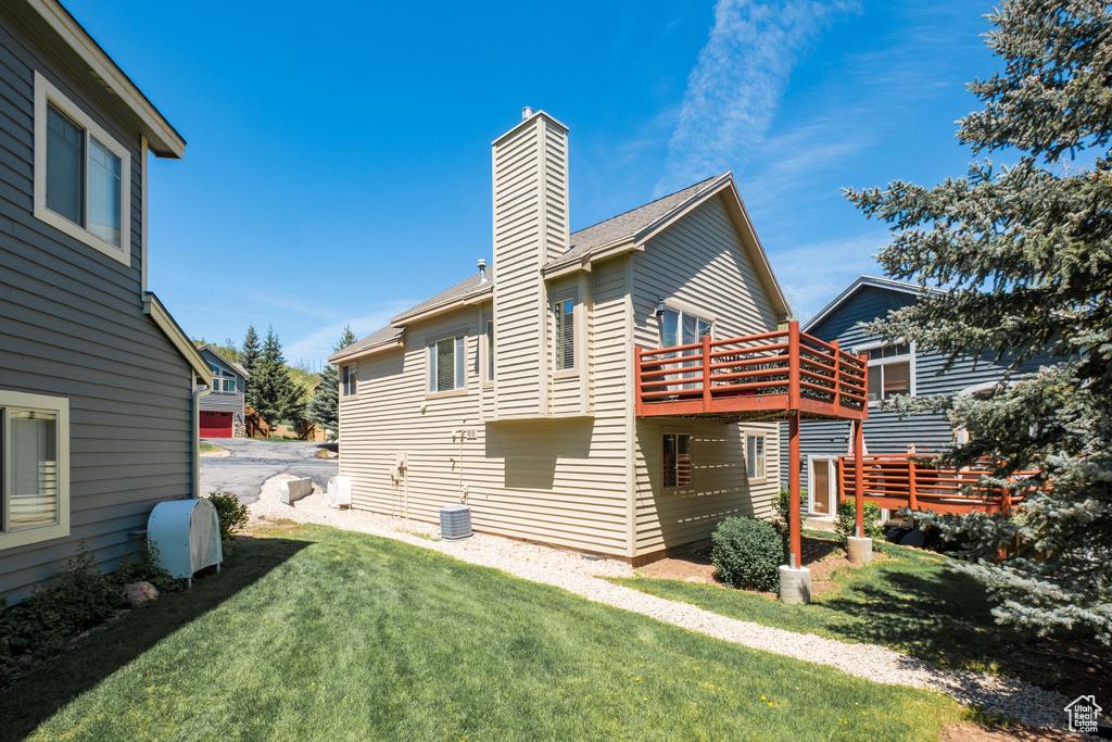 Rear view of property with a chimney and a lawn