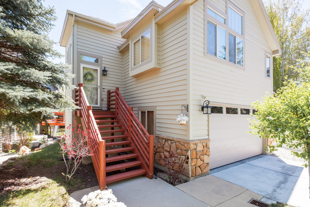 View of front of house with a garage, stone siding, and driveway