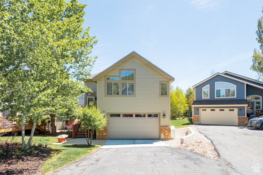 View of front of house featuring a garage, stone siding, driveway, and stairway