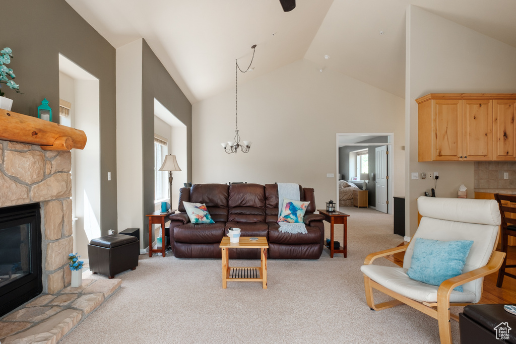 Living room featuring light colored carpet, a chandelier, high vaulted ceiling, and a fireplace
